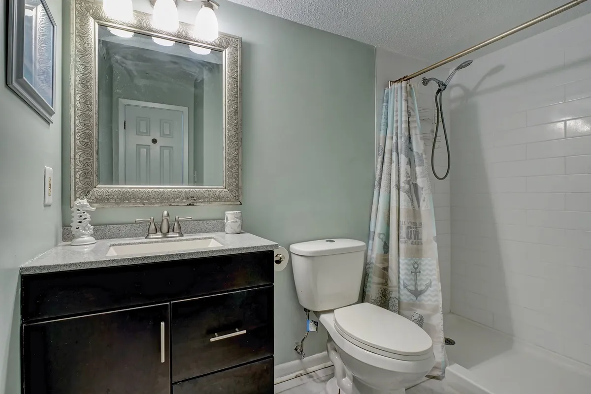 A modern bathroom with a sleek vanity and sink, a large mirror, a shower area, and contemporary fixtures. The bright, fresh mood of the space exemplifies both comfort and style—ideal for morning rituals or winding down after a day by the sea.