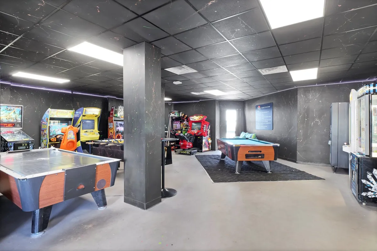 An inviting indoor game room with arcade machines, a pool table, air hockey, and a seating area. The room buzzes with energy and possibilities for friendly competition and memorable game nights.